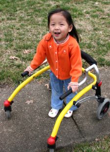 Niña sonriente que usa un andador en un parque.