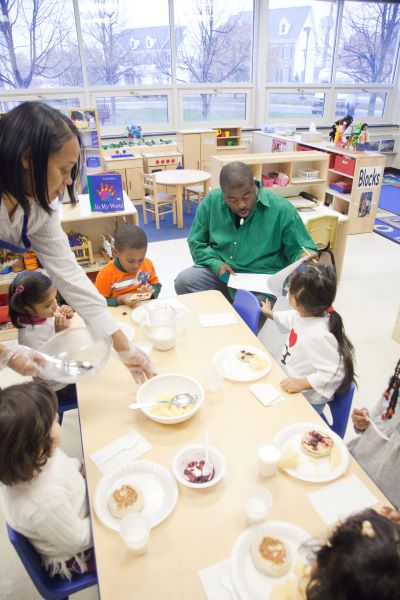 Niños sentados en una mesa a los que se les sirve comida.