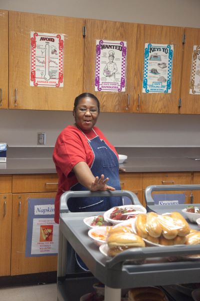 Nutrition staff member preparing a cartful of prepared food.