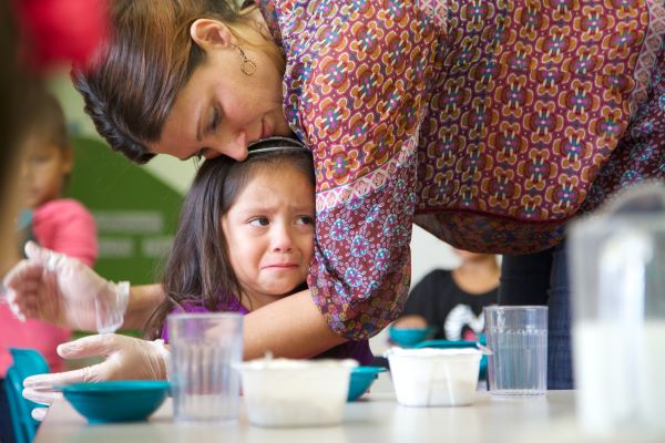 A worried child being hugged by a food service staff member.