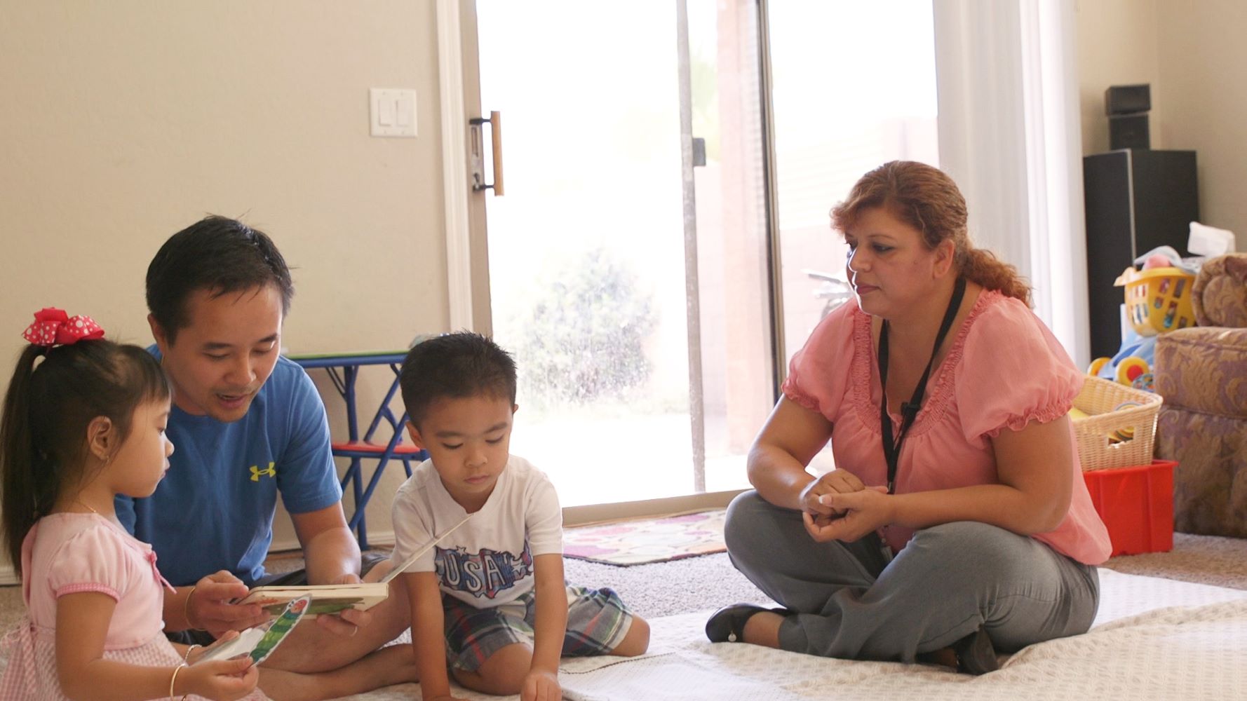 Home visitor observing father with children reading a book.