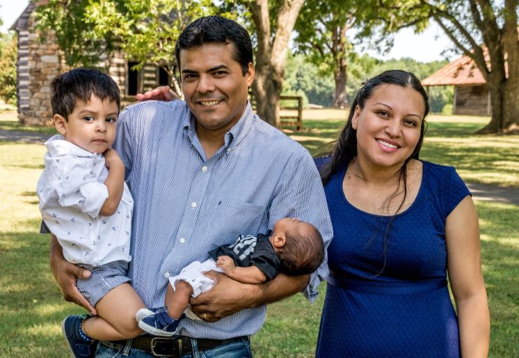 Mom along with dad who is holding their infant and toddler in each arm.