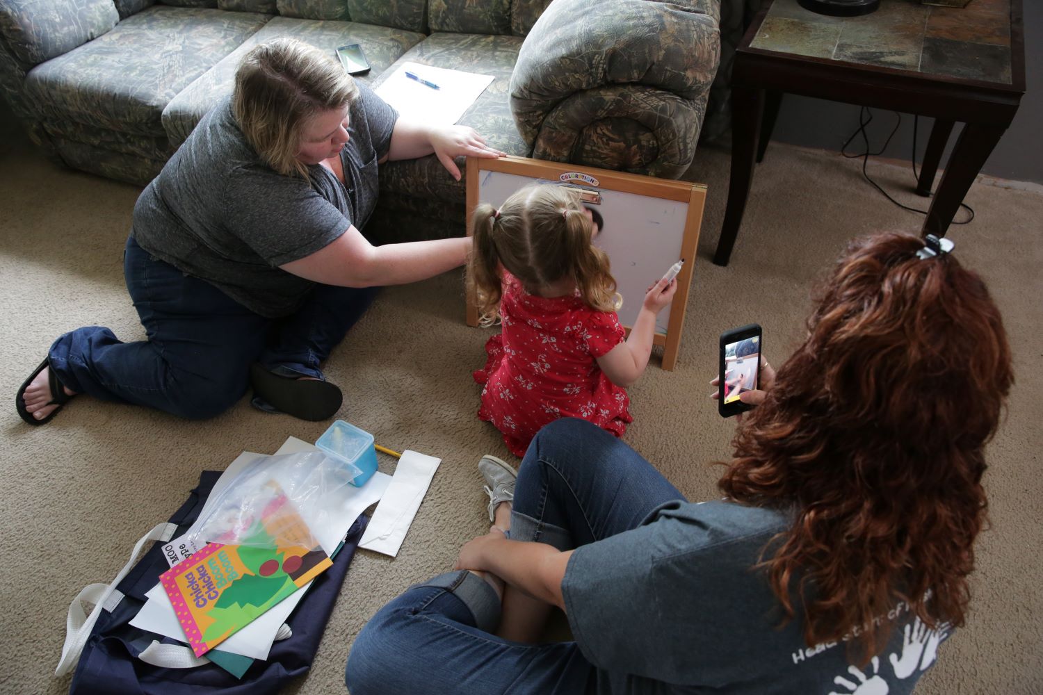 Home visitor using a cell phone to video a child and mother play interaction.