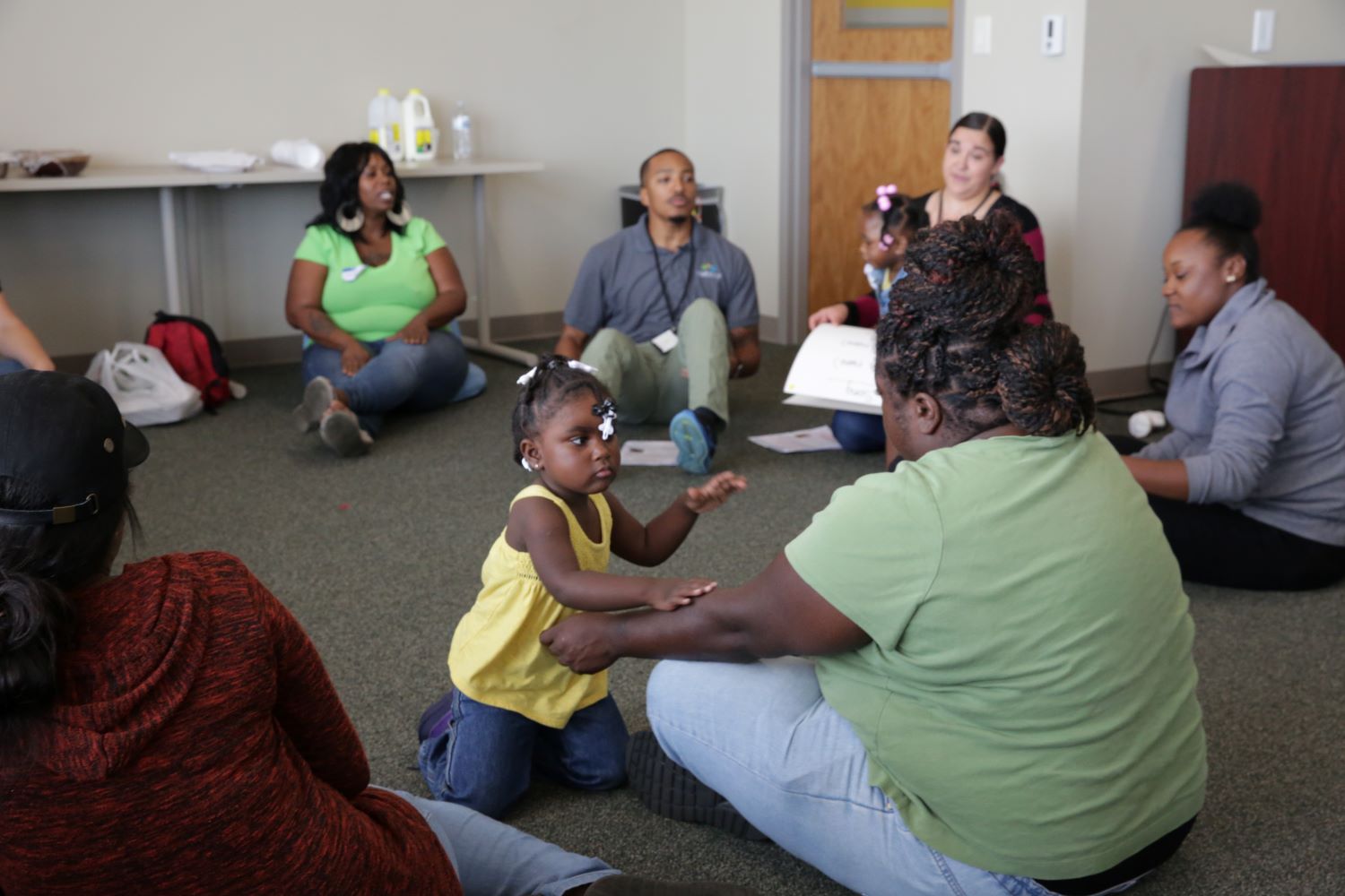 Teachers and children sitting on floor in a semi-circle.