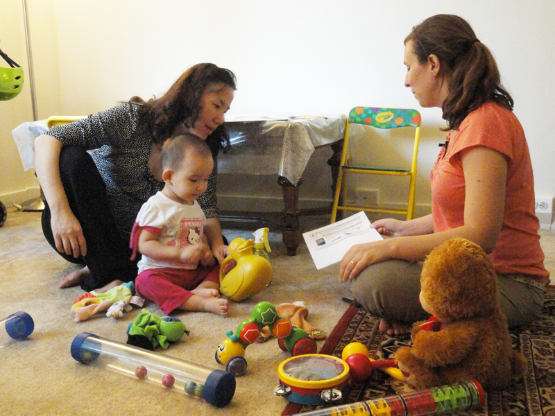 Mother and child along with home visitor, sitting on the floor talking.