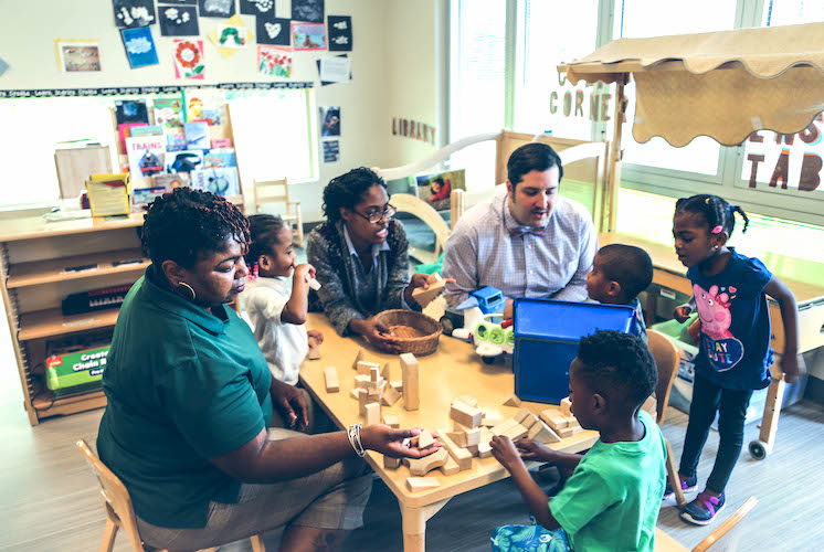 Instructors and kids playing with building blocks