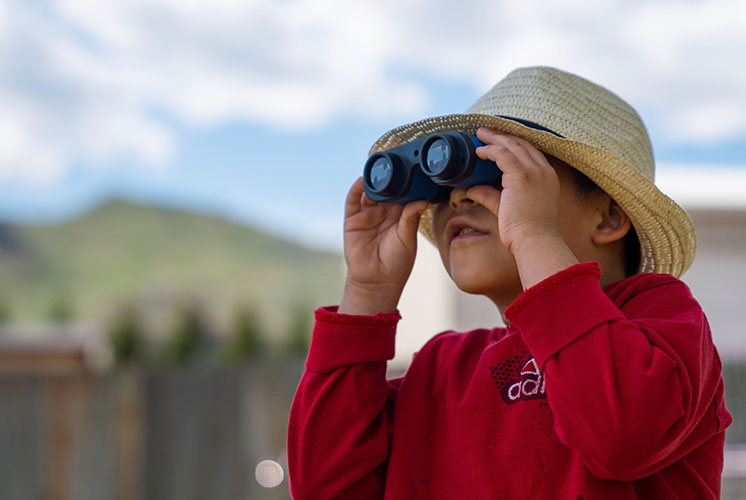 a boy is looking at the sky through binoculars