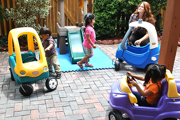 while an adult supervises, kids play outside on patio inside mobile toy cars