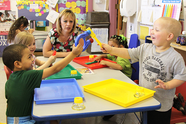 Teacher and kids around table play with magnets