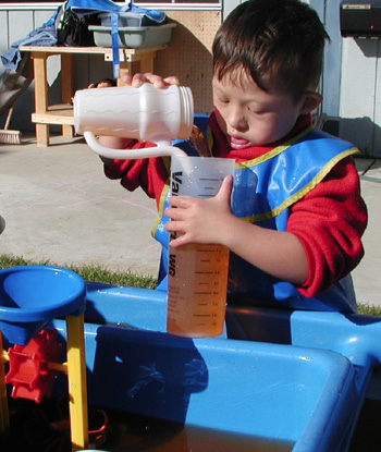 Little kid pouring liquid into bottle