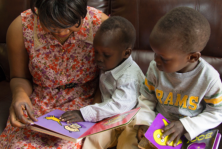 A mom reads with two toddler boys