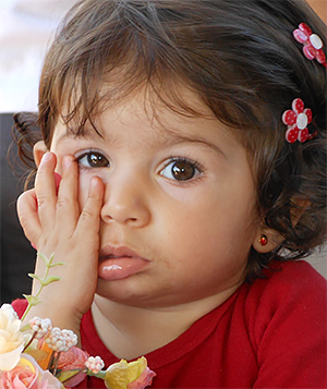 Little girl holding the side of her mouth