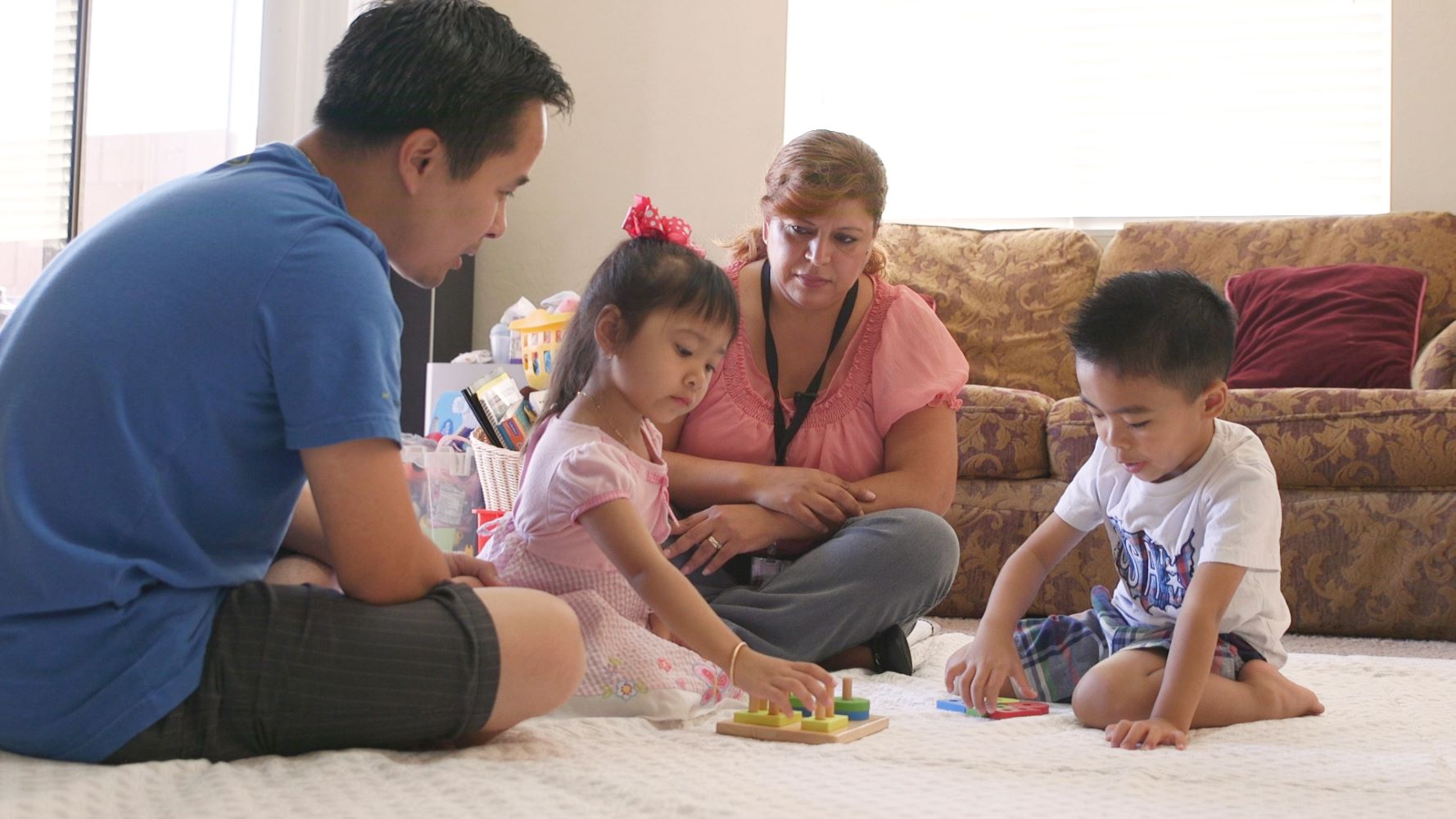 Padres e hijos en el piso de su sala de estar jugando.