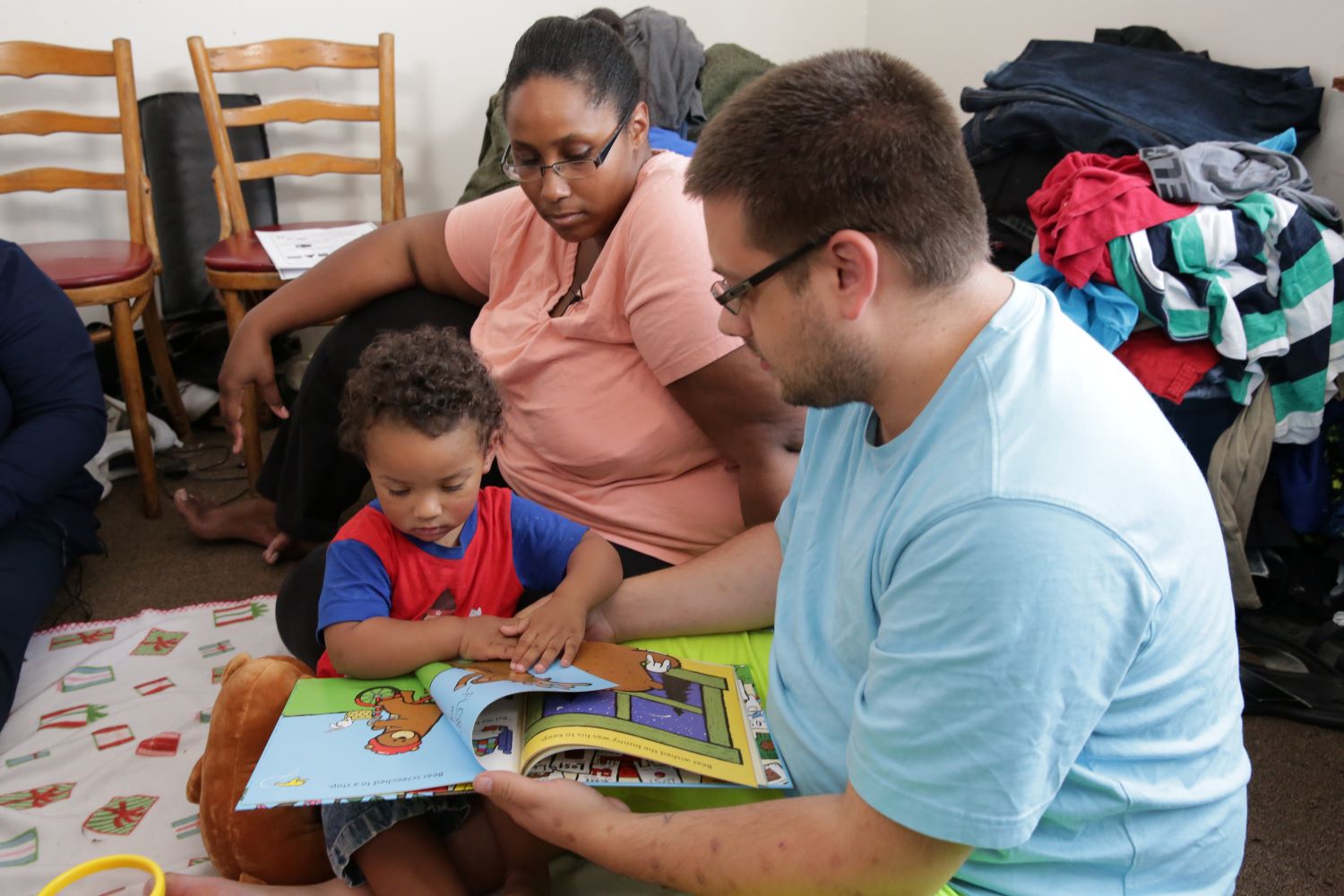 Padres leyendo con su hijo en el piso.