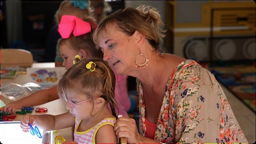 Teacher assisting toddler letters' learning