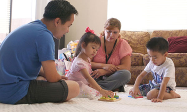 Una visitadora del hogar y un padre con sus hijos haciendo rompecabezas