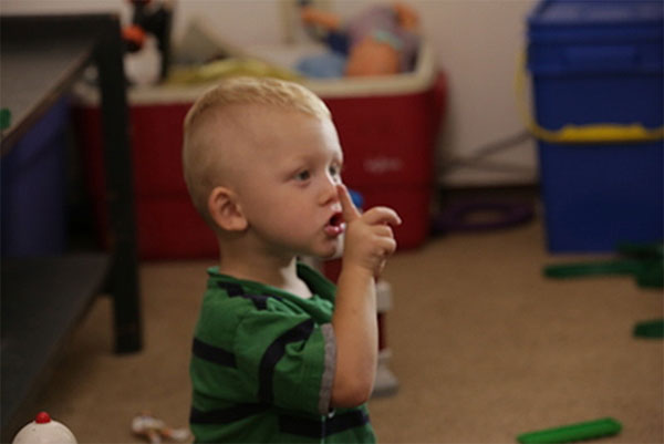 Toddler boy holding up a finger to be quiet