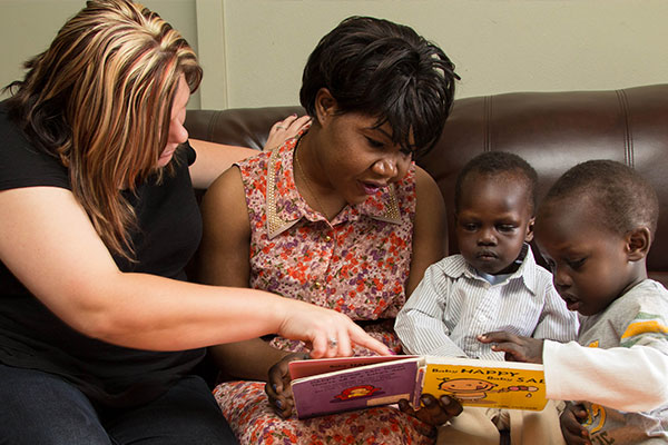 Home visitor helping a parent and child read a book