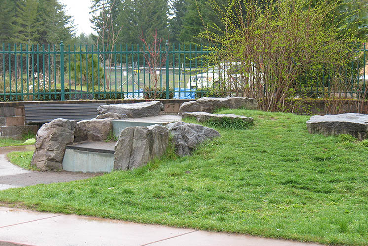 a sloping lawn with rocks and steps