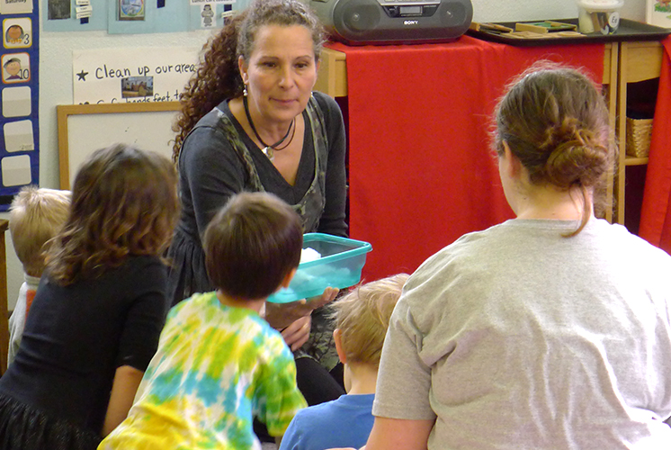 A teacher shows snow in a container to group of kids