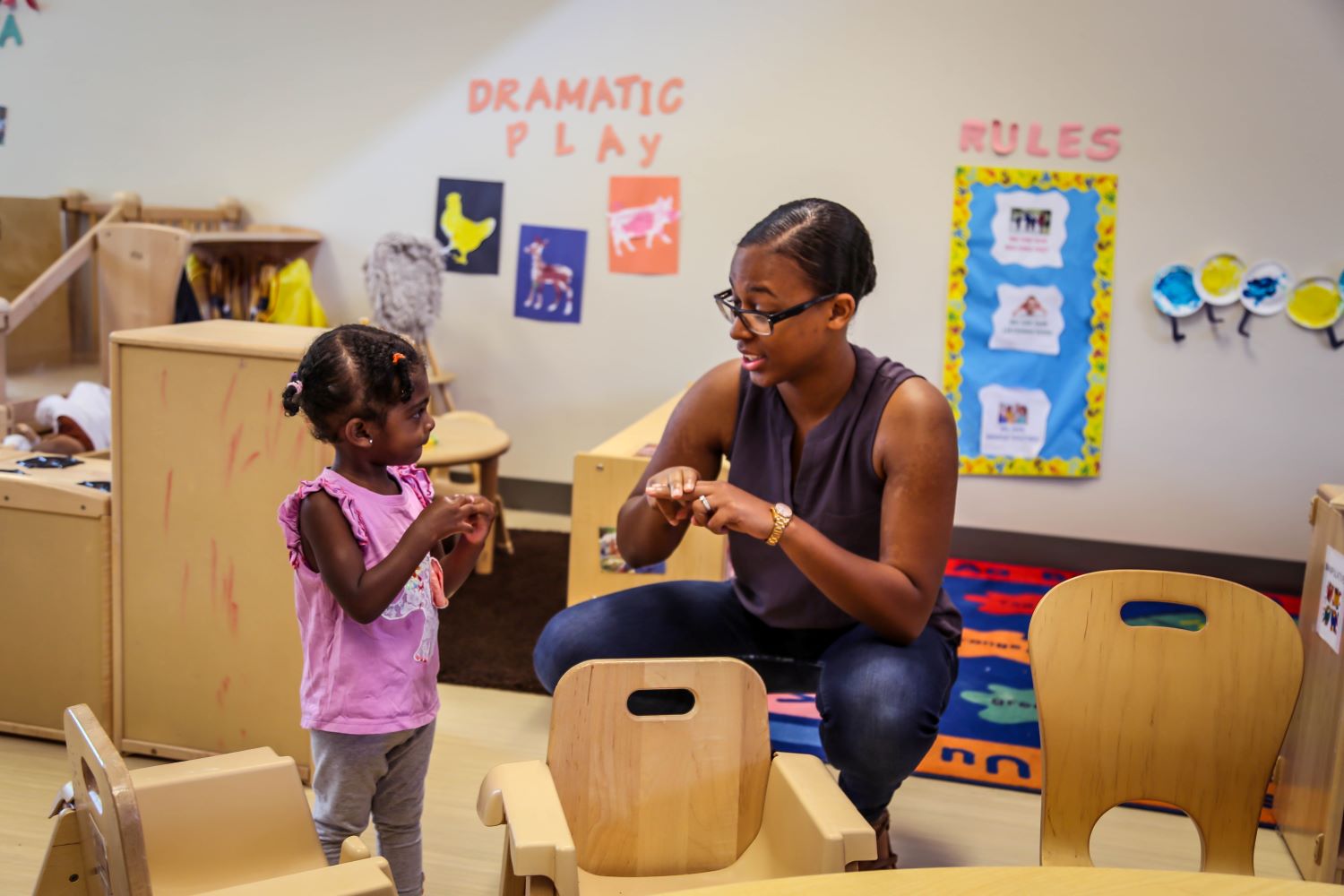 Teacher showing child how to make symbols with fingers.