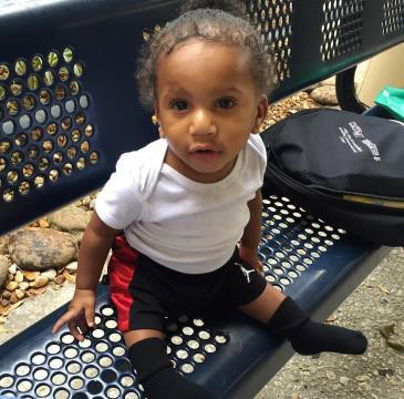 a toddler sits on a bench outdoors