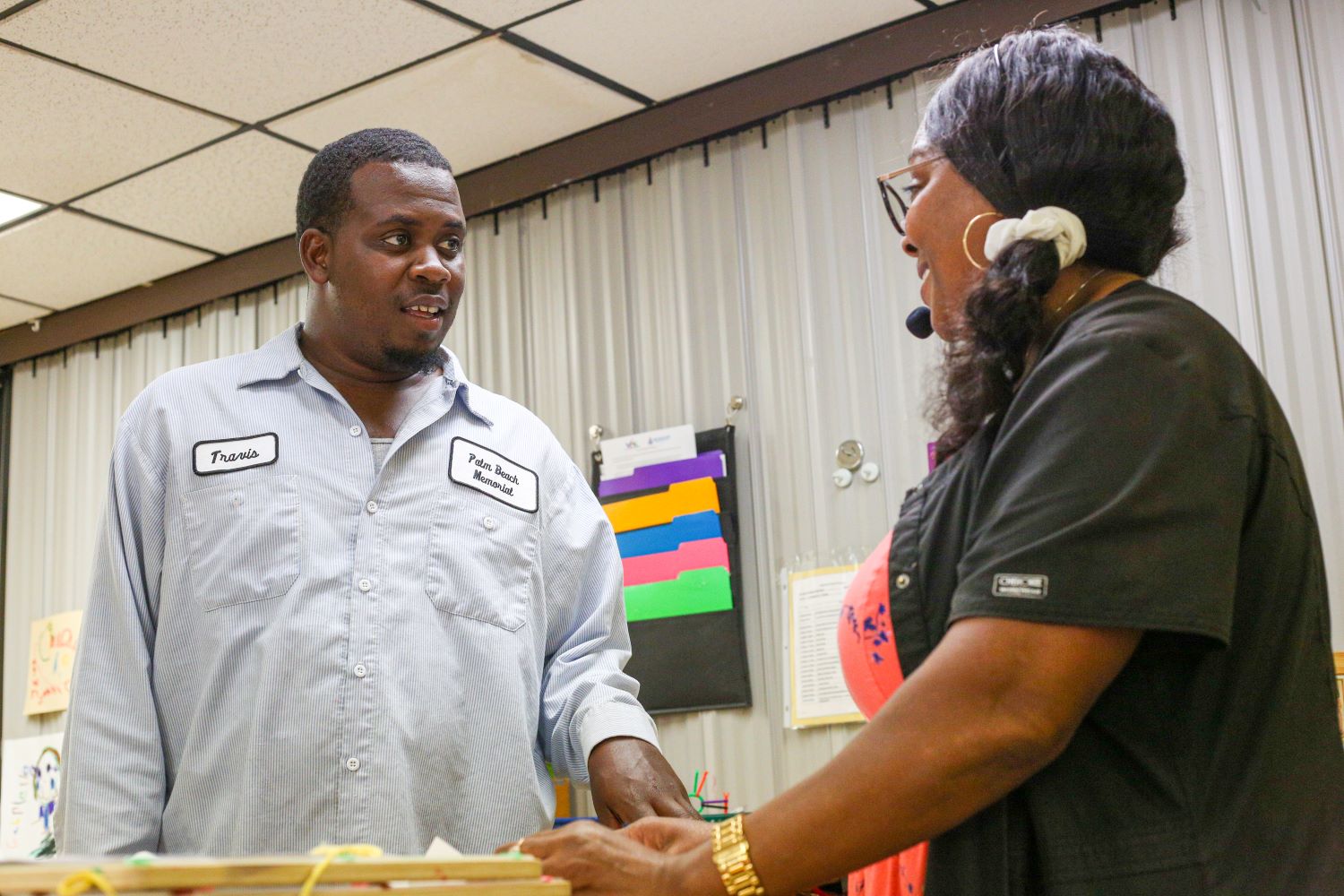 Two smiling adults talking at Head Start center.