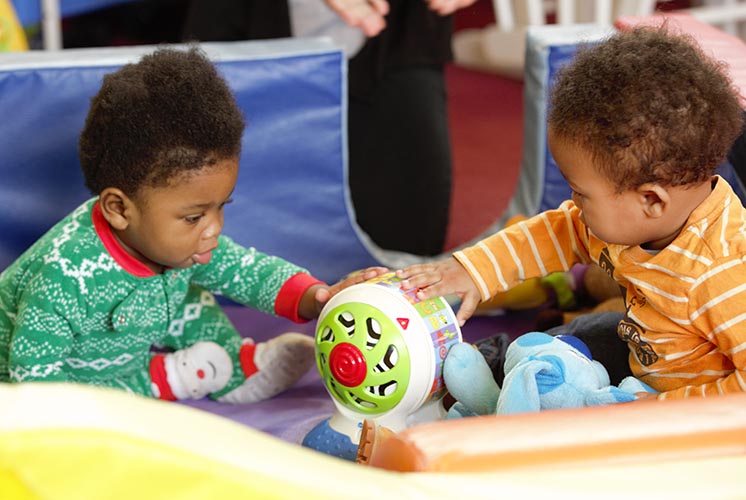 two babies play with a toy together