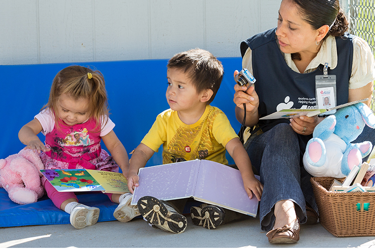 dos niños con los libros junto al maestro