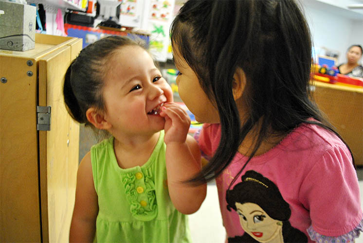 two young girls talk and laugh together