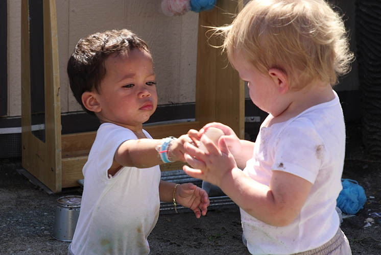 two children with serious expressions are holding and touching the same object