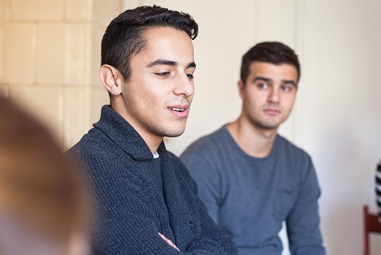 Focusing in close on two men in a group therapy setting