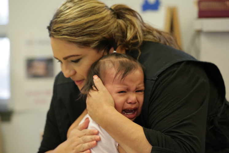 Mujer abrazando contra el pecho a un niño llorando