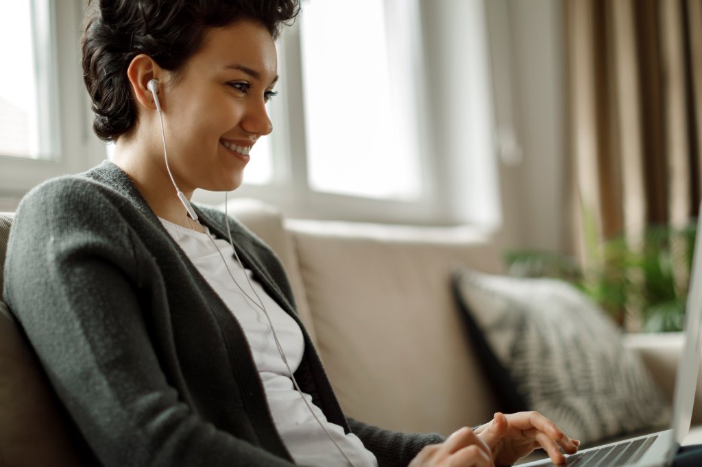 Mujer usando su portátil y con auriculares