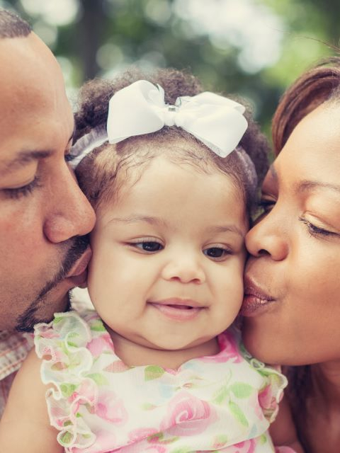 Madre y padre besando a su hijo.