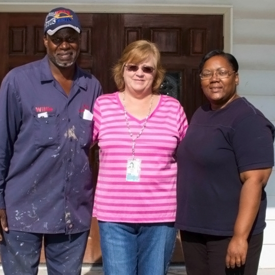 Three people from renovation team in front of building